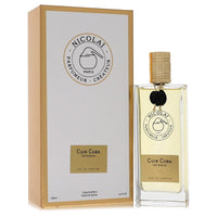 Dark leather bottle with gold cap sitting on a wooden surface by The Fragrance Avenue.