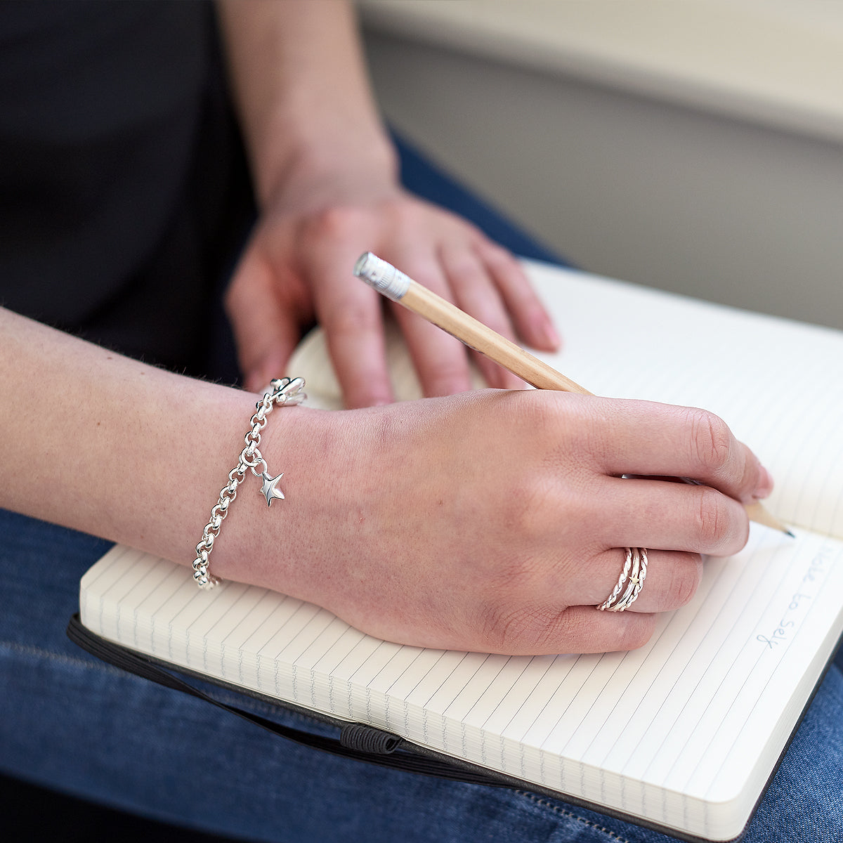 A silver belcher chain charm bracelet featuring a star-shaped charm, styled with a delicate dangle, by Scarlett Jewellery.